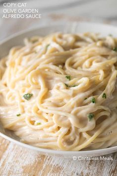 a white bowl filled with pasta on top of a wooden table