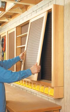 a man is working on a piece of wood in a shop with tools and pegs