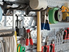 there are many different tools hanging on the pegs in this garage storage area with hooks, wrenches, and pliers