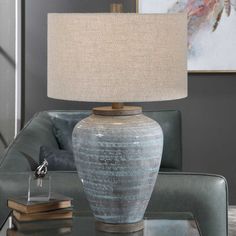 a table lamp sitting on top of a glass table next to a gray couch in a living room