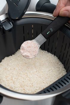 rice being cooked in an air fryer with a ladle scooping it into the pot