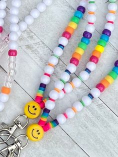 two necklaces with smiley faces on them are next to a pair of scissors and some beads