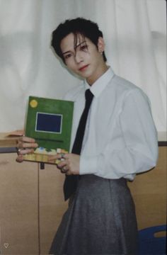 a woman in a dress shirt and tie holding up a green box with a computer screen on it