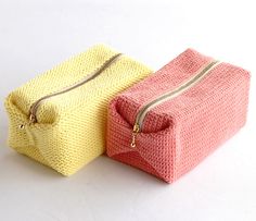 two knitted bags sitting next to each other on a white surface with zippers