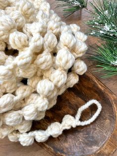 a crocheted object sitting on top of a wooden board next to a pine tree