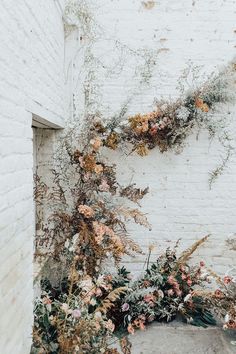 flowers growing on the side of a white brick building