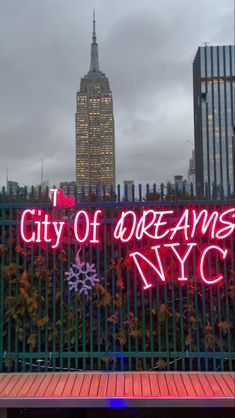 the city of dreams sign is lit up in red and purple lights on a fence