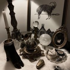 a table topped with lots of different items next to a mirror and candle holder on top of a white fur covered floor