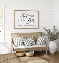 a wooden bench sitting in front of a white wall with pillows on top of it