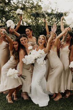 a group of women standing next to each other holding bouquets and posing for the camera