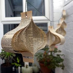 three paper lanterns hanging from a string outside with potted plants in the foreground