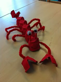 a red crab made out of legos sitting on top of a wooden table