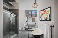 a bath room with a tub a sink and a painting on the wall above it