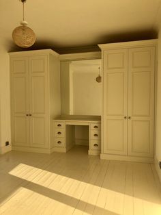 an empty room with white cupboards and drawers in the center, light shining on the floor