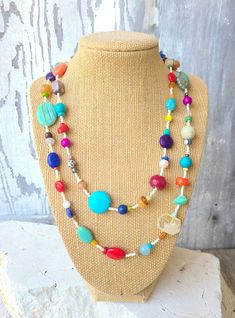 "Two pretty graduated strands of multi-color, semi precious stones make up this semi precious stone necklace.  Just about every stone you can imagine, turquoise, garnet, lapis lazuli, pearls, chrysoprase, red coral, and carnelian, just to name a few. In between the stones are cream/gold color Japanese seed beads. The necklace measures 18\" on the shortest length and 22\" on the longest length. Both  strands are connected with a large silver toggle clasp.  It is strung on an 18 strand nylon coate Colorful Beaded Necklaces With Natural Stones, Colorful Natural Stone Beaded Necklaces With Round Beads, Bohemian Rainbow Necklaces With Natural Stones, Multicolor Bohemian Long Turquoise Necklace, Handmade Multicolor Long Turquoise Necklace, Bohemian Rainbow Gemstone Beaded Necklace, Multicolor Turquoise Necklace With Round Beads For Beach, Adjustable Multicolor Beaded Turquoise Necklace, Multicolor Turquoise Beach Necklace With Round Beads