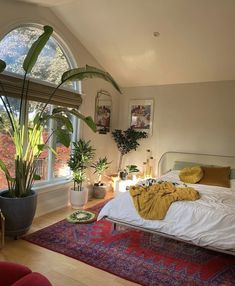 a bedroom with a large bed and lots of plants in the window sill next to it