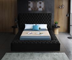 a bed with blue and white pillows in a black colored room, it is made up