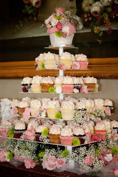 three tiered trays filled with cupcakes and flowers