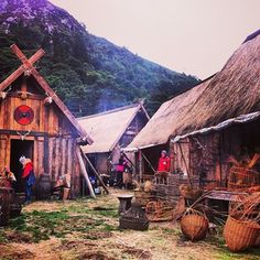 people are standing in front of huts with thatched roofs and straw baskets on the ground