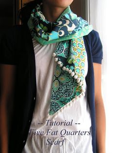 a woman wearing a white t - shirt with a green and blue scarf around her neck