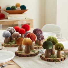 a table topped with different colored mushrooms on top of wooden bases next to plates and glasses