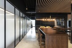 an empty restaurant with wooden tables and bar stools, along with glass partitions on the walls