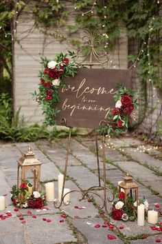 a sign that says welcome to the wedding surrounded by candles and flowers on a stone path