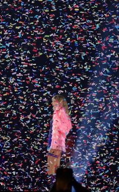 a woman standing on top of a stage with confetti all over her body