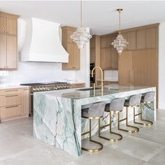 a large kitchen with marble counter tops and gold barstools in front of an island