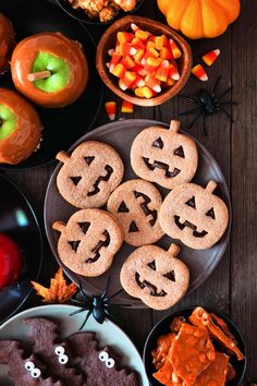 halloween treats are arranged on plates with candy and candies in the bowl next to them