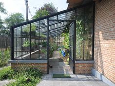 a brick building with glass walls and plants in it