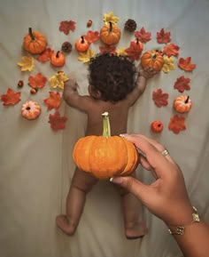 a person holding a pumpkin in front of a baby