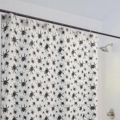 a shower curtain with black and white spider webs on it, in a bathroom