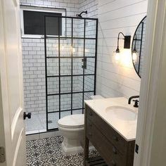 a white toilet sitting next to a walk in shower under a bathroom mirror with lights on it