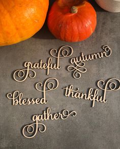 the words grateful autumn are spelled in cursive writing next to two pumpkins