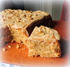 a piece of cake with frosting and nuts sitting on top of a cutting board