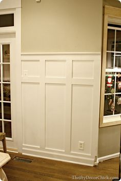 an empty room with white paneling and wood floors