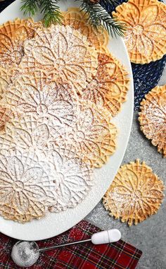 a white plate topped with pies covered in powdered sugar next to christmas decorations