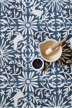 a bowl of blueberries and a wooden spoon on a patterned tile floor