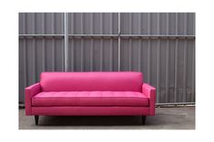 a pink couch sitting in front of a metal wall