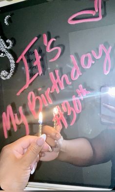 a person holding a lit candle in front of a birthday sign