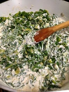 spinach and cheese cooking in a pan with a wooden spoon