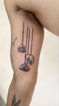 a man's leg with tattoos on it and skulls hanging from the top of them