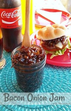 a table topped with two hamburgers and a jar of coke