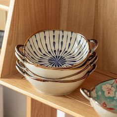 a stack of bowls sitting on top of a wooden shelf next to other plates and bowls