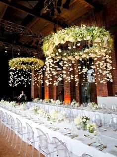 the tables are set with clear chairs and white tablecloths for an elegant event