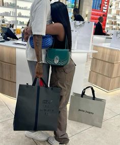 a man and woman standing next to each other with bags in front of their backs