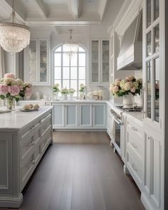 a large kitchen with white cabinets and flowers in vases