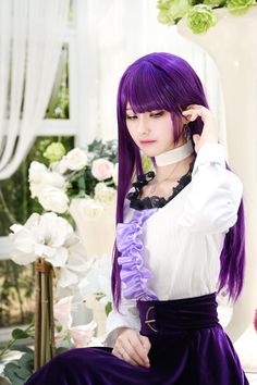 a woman with purple hair wearing a white shirt and purple skirt sitting on a chair