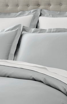 a bed with grey sheets and white pillows